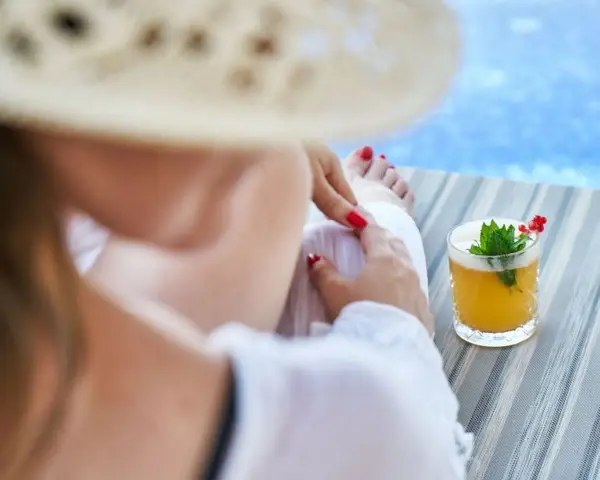 Relaks przy basenie z drinkiem w hotelu dla dorosłych Polska. Kobieta w słomkowym kapeluszu odpoczywa na leżaku.