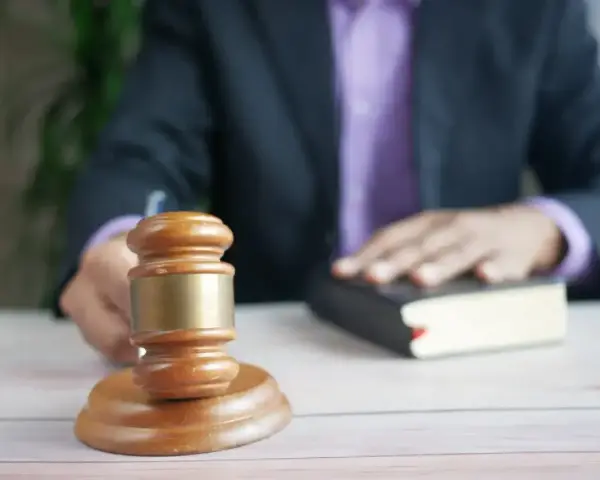 Sędzia kładzie rękę na księdze, obok młotka. Czas oczekiwania na uprawomocnienie wyroku karnego może być różny.