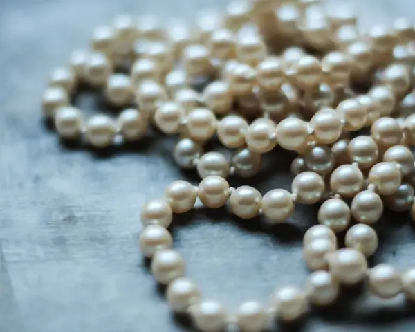 Collana di perle su sfondo grigio. Scopri come pulire la madreperla per mantenerla splendente.