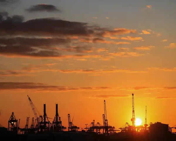 Silhouetten von Kränen im Hamburger Hafen bei Sonnenuntergang. Perfekt für die Pfingstferien in Hamburg.