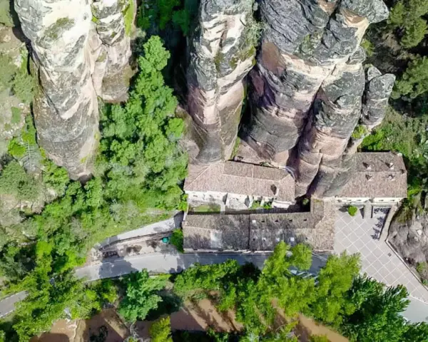 Vista aérea del **barranco de la Hoz, Guadalajara**, con edificios integrados en las rocas y vegetación exuberante.