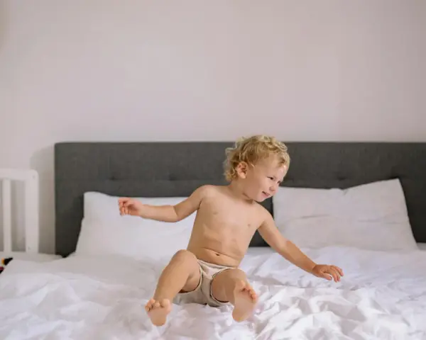 Chłopiec w majtkach na łóżku, ciekawy świata. Czas na odpieluchowanie, nauka samodzielności.