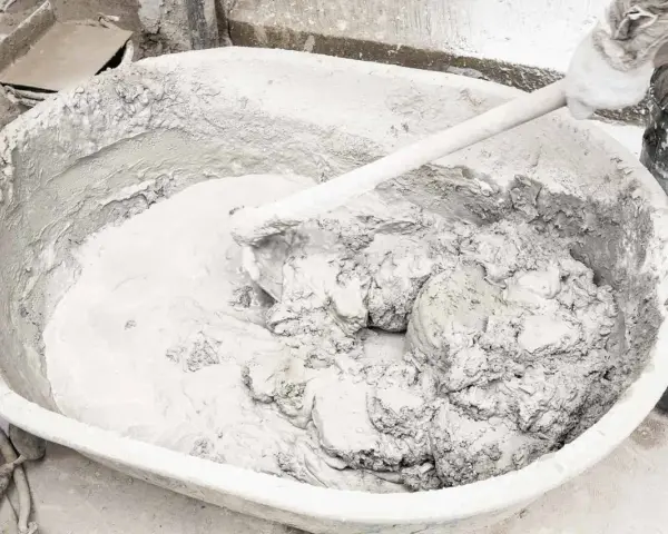 Mieszanie wapna gaszonego z wodą w dużej misie, tworząc gładką masę do prac budowlanych.