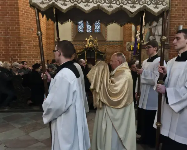 Uroczysta procesja w kościele, kapłan niesie monstrancję okrytą złotym welonem. To symboliczna rezurekcja.