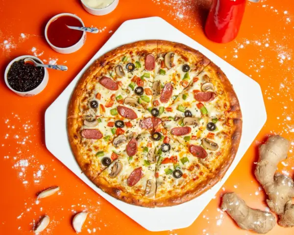 Gotowa pizza z kiełbasą, pieczarkami i papryką, obok sosy i imbir – idealne składniki na pizzę.