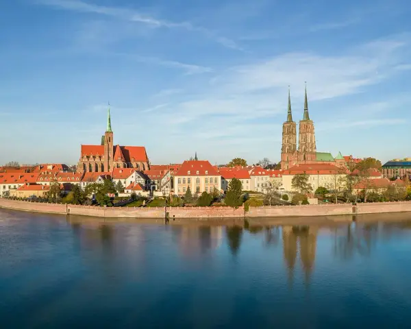 Wrocław stare miasto z katedrami i Ostrów Tumski nad Odrą, odbijające się w spokojnej wodzie.