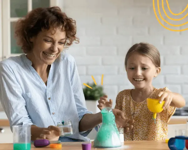 Mama i córka śmieją się, wykonując spektakularne eksperymenty dla dzieci z zieloną pianą w probówce.