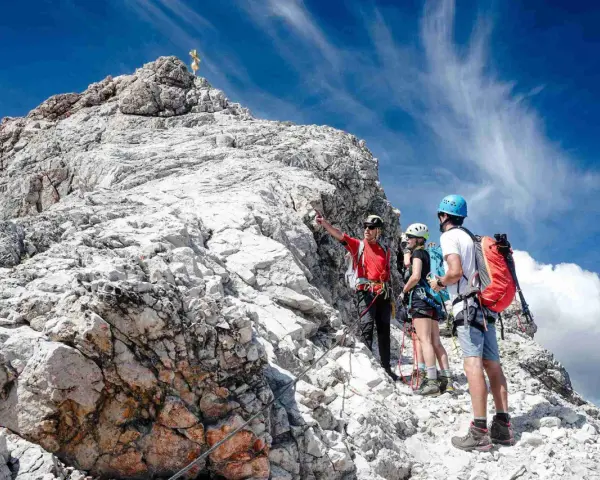 Bergsteiger am Gipfel der Zugspitze ohne Klettersteig. Ein Führer erklärt den Weg.