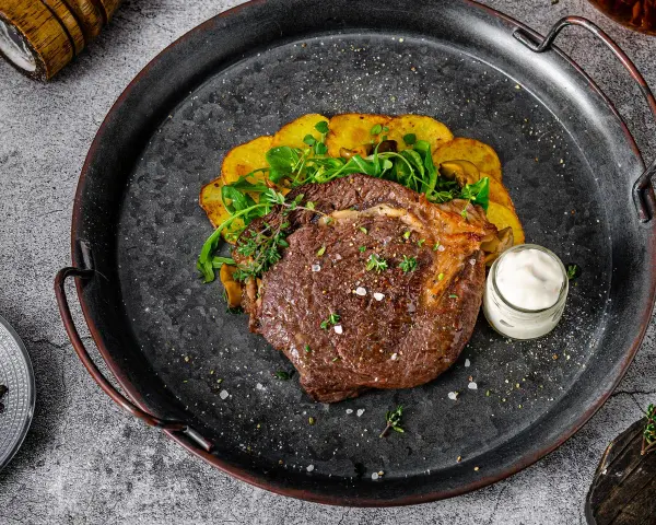 Un jugoso lomo bajo de vaca a la parrilla, acompañado de patatas crujientes y una salsa cremosa. ¡Un festín para los sentidos!