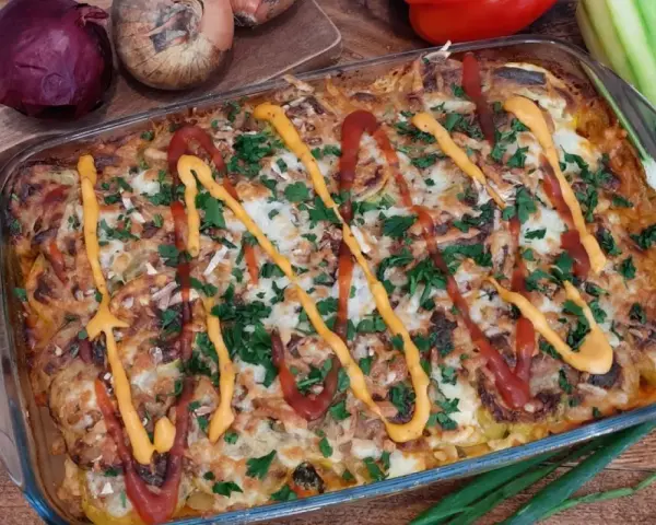 Pyszna keto zapiekanka z mięsem mielonym i cukinią, polana ketchupem i musztardą, posypana natką pietruszki.