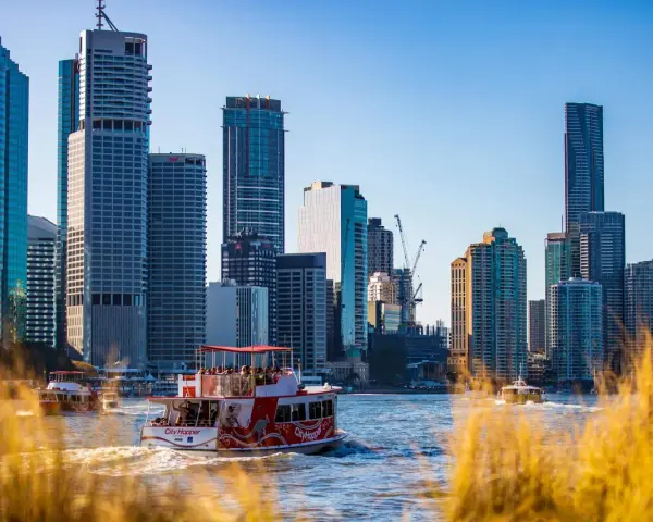 Ein Auslandssemester in Australien: Boote auf dem Fluss vor der Skyline von Brisbane mit modernen Hochhäusern.