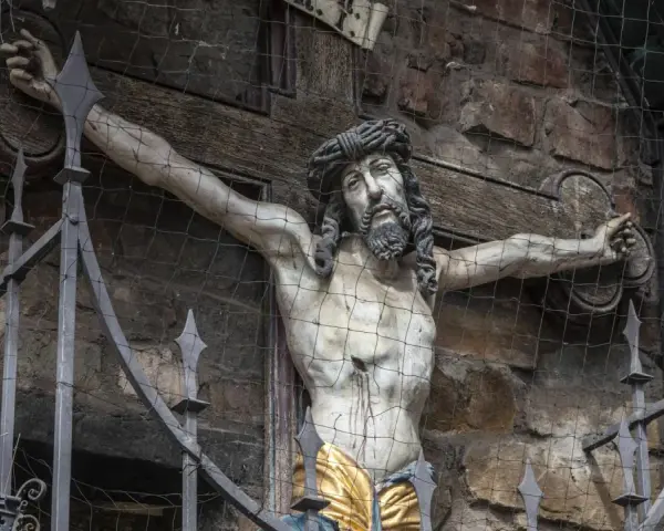 Kreuzigungsgruppe mit Jesus, der die Frage aufwirft, wie alt war Jesus als er starb. Davor ein schmiedeeiserner Zaun.