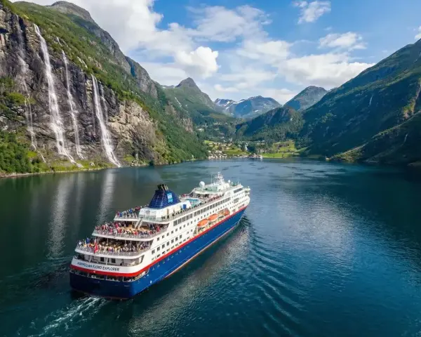 Rejs statkiem "Norwegian Fjord Explorer" przez malownicze fiordy Norwegii, z wodospadami i zielonymi zboczami.