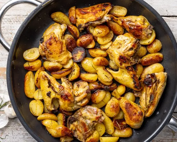 Pollo con patate in padella, dorato e saporito, con erbe aromatiche. Un piatto rustico e invitante.