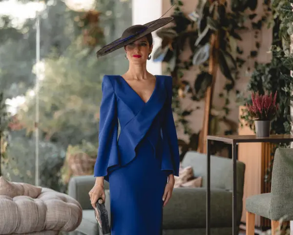 Elegante mujer con vestido azul klein y sombrero, ideal para saber como combinar un vestido azul klein para una boda.