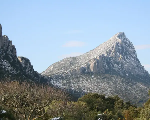 Vue hivernale du pic Saint-Loup, ses pentes couvertes de neige contrastant avec le ciel bleu.