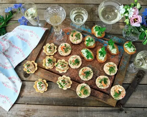 Små, läckra tilltugg till bubbel, serverade på en rustik bricka med blommor och glas. Perfekt för festliga tillfällen.
