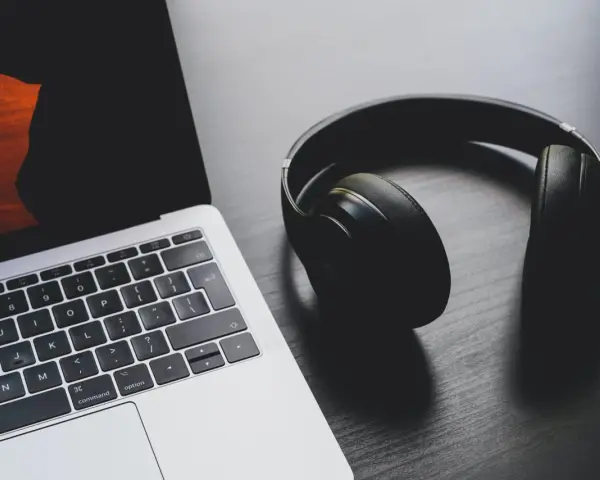 Słuchawki leżą obok laptopa. Może to być sygnał, że występuje brak dźwięku w laptopie i potrzebne są słuchawki do słuchania.