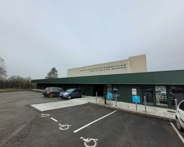 Devant les archives départementales 52, deux voitures sont garées près de l'entrée. Le bâtiment porte l'inscription "ARCHIVES DEPARTEMENTALES DE LA HAUTE-MARNE".