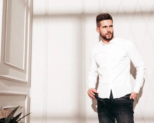 Mężczyzna w białej koszuli i jeansach, prezentujący styl slim fit.