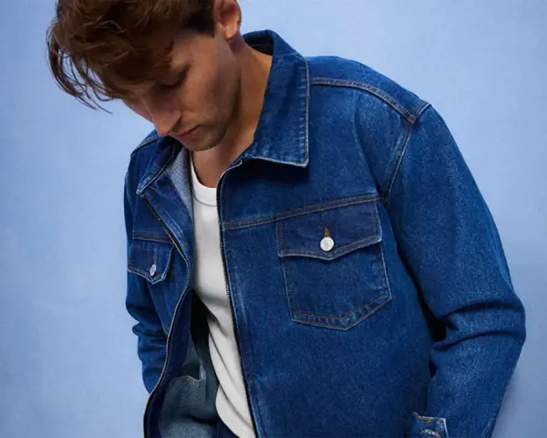 Mężczyzna w dżinsowej kurtce, idealnej do stworzenia uniwersalnej szafy kapsułowej. Klasyczny krój i niebieski denim.