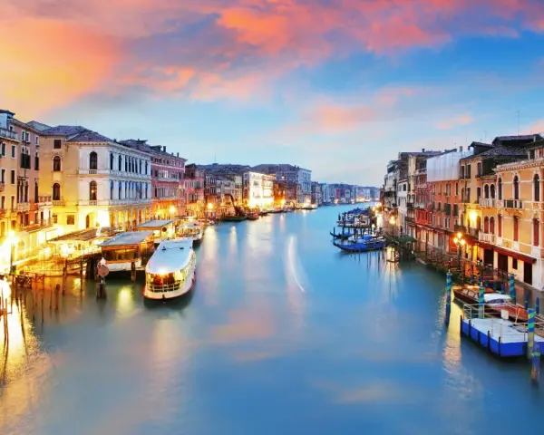 Il Canal Grande di Venezia, con le sue opere d'arte architettoniche illuminate al tramonto, accoglie gondole e vaporetti.