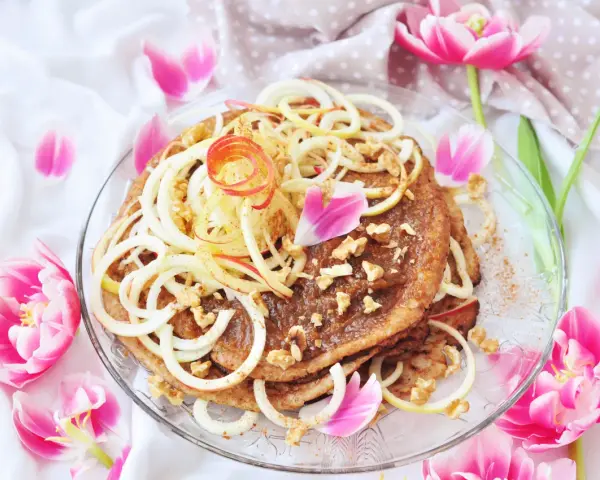 En vacker pannkakstårta med äpple, kanel och valnötter, perfekt för ett pannkakstårta recept. Omgiven av rosa tulpaner.