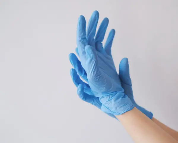 Ręce w niebieskich rękawiczkach nitrylowych, idealnych jako rękawiczki do laboratorium chemicznego.