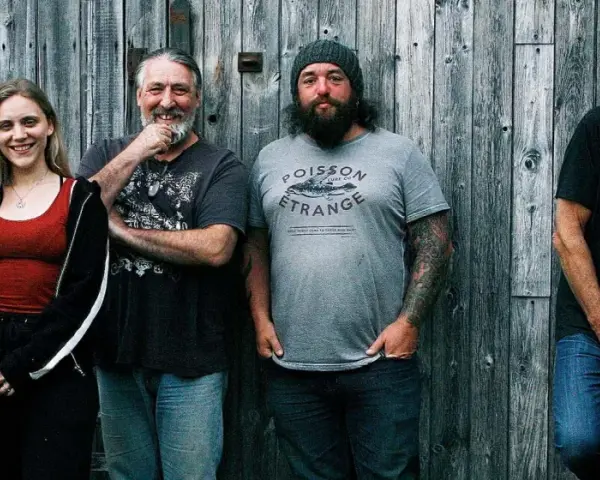 Le groupe de Robert Plant, avec ses musiciens, pose devant un mur de bois.