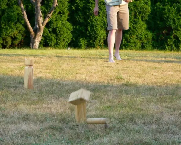 Holzfiguren für Outdoor-Spiele im Gras. Ein Spielstein ist in der Luft, bereit für das nächste Spiel.