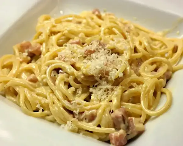 Pyszne spaghetti carbonara z kawałkami guanciale i parmezanem. Idealna śmietana do carbonary to sekret tego dania.