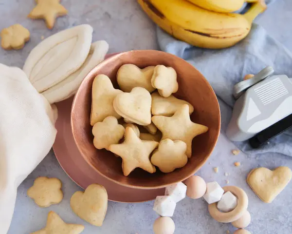Kleine Sterne und Herzen: Baby Kekse backen ab 6 Monate. Dazu Bananen und ein Holzspielzeug.