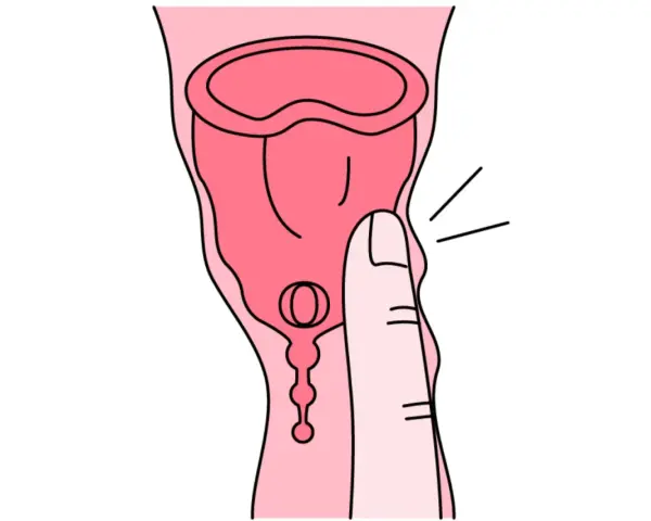 Dłoń naciska na kubeczek menstruacyjny. Tworzywo TPE, choć popularne, może budzić pytania o jego szkodliwość.