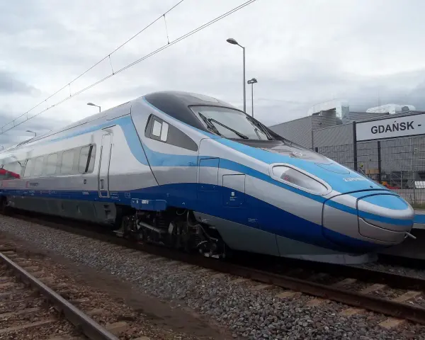 Nowoczesny pociąg Pendolino w kolorach biało-niebieskim stoi na torach przy peronie.