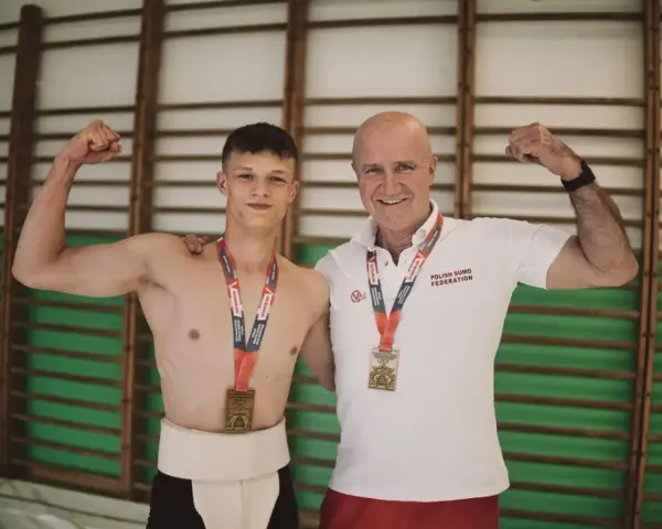 Dwóch zapaśników sumo z medalami, młody zawodnik w tradycyjnym stroju i trener. Prawdopodobnie świętują rekord Polski suma.