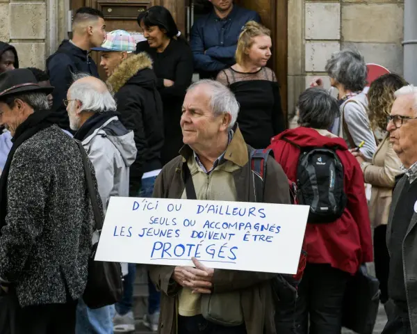 Un homme tient une pancarte "D'ici ou d'ailleurs, seuls ou accompagnés, les jeunes doivent être protégés", soutenant un centre d'accueil pour mineur.