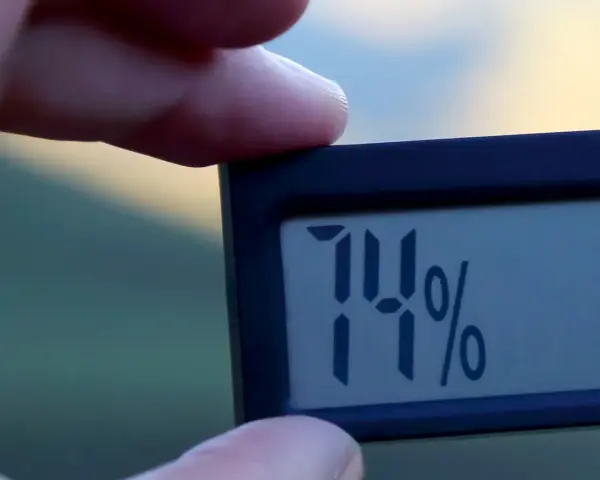 En digital hygrometer visar 74%, vilket indikerar normal luftfuktighet inomhus.