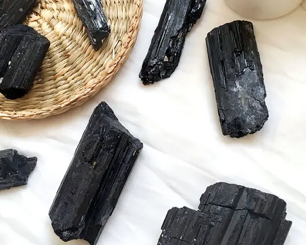 Cristales de turmalina negra, algunos en una cesta de mimbre, listos para atraer el amor y la protección.