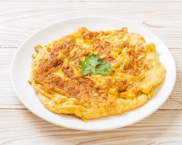 Frittata dorata e soffice, preparata in friggitrice ad aria, guarnita con un ciuffo di prezzemolo fresco.