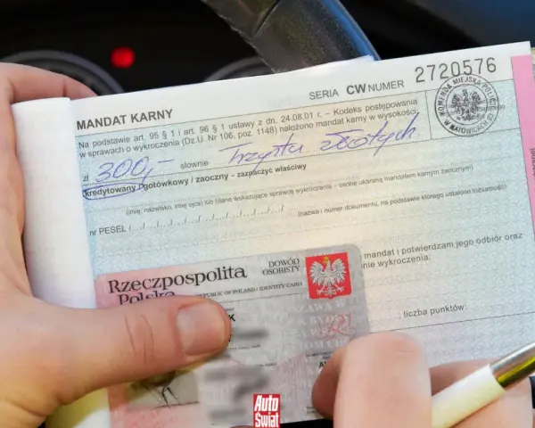 Dłoń trzyma mandat karny i dowód osobisty.