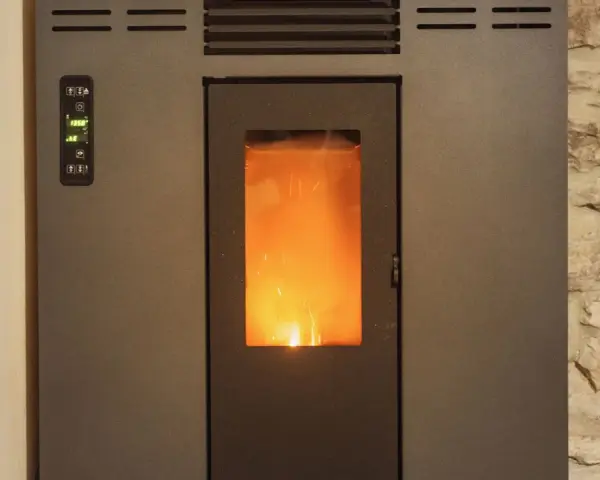 Stufa a pellet con fiamma viva visibile. Il pannello di controllo mostra "19.5°". La distanza candeletta stufa pellet è ottimale per l'accensione.