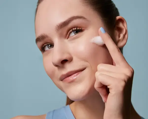 Donna applica schiuma sul viso, un gesto essenziale per la skincare routine mattina e sera. Pelle luminosa e curata.