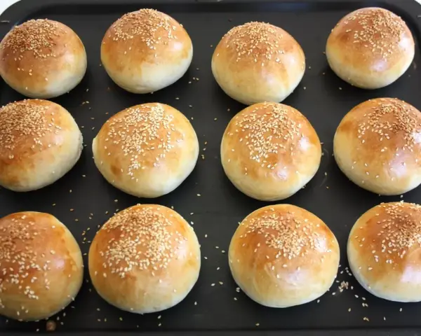 Nybakade frallor med sesamfrön på en plåt, redo att ätas. Perfekt för att baka frallor till frukost eller fika.