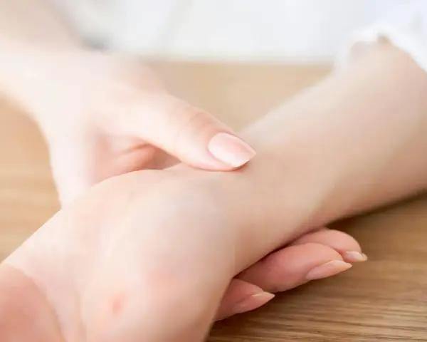 En elitidrottare känner sin vilopuls. En hand vilar på handleden, fingrarna känner efter pulsslag.
