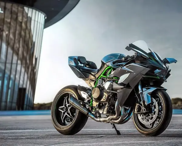 Kawasaki H2R – maszyna, która w mgnieniu oka osiąga 100 km/h. Czarny, sportowy motocykl z zielonymi akcentami na ramie, zaparkowany przed nowoczesnym budynkiem.