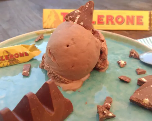 Schokoladeneis mit Toblerone-Stücken und einer ganzen Toblerone-Tafel auf einem Teller.