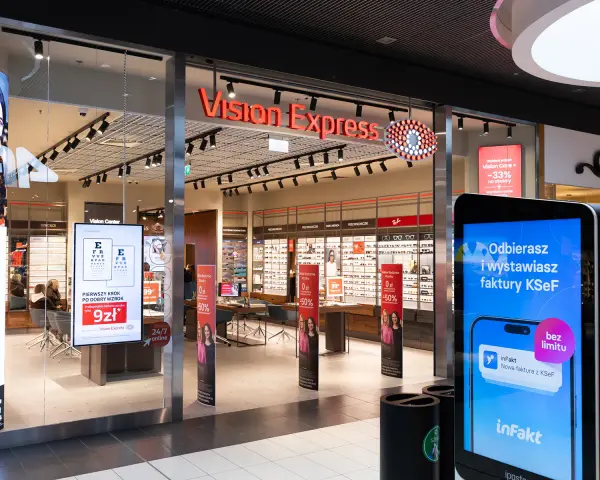 Witryna sklepu Vision Express z ekspozycją okularów i ekranem informacyjnym.
