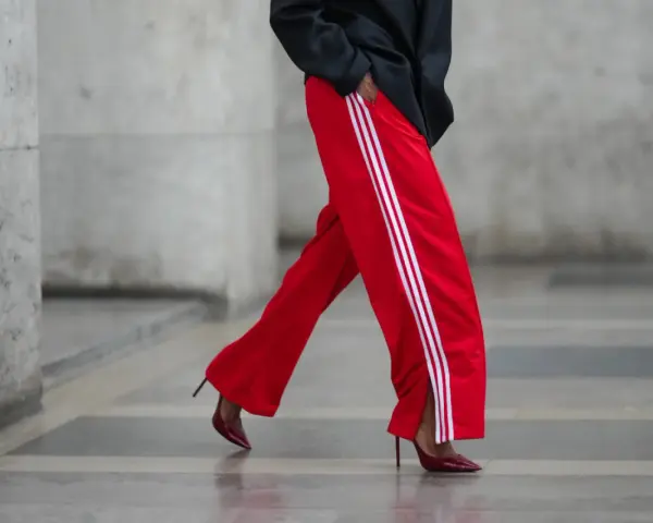 Czerwone spodnie dresowe z białymi lampasami i eleganckie szpilki. Odważne połączenie, które odpowiada na pytanie: jakie buty do dresów?