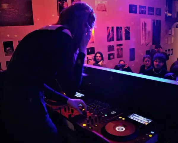 Une dj femme aux platines, ambiançant une foule dans un club.