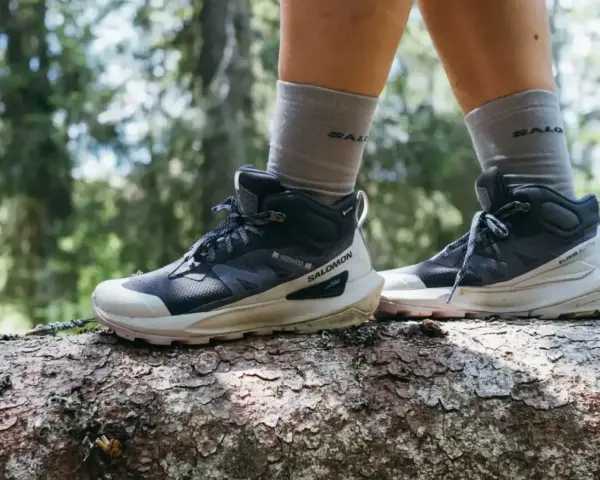 Buty trekkingowe Salomon na pniu drzewa w lesie. Salomon to firma znana z wysokiej jakości obuwia outdoorowego.
